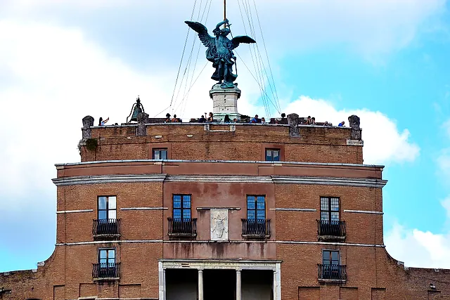 Die Spitze der Engelsburg: die Bronzestatue des Erzengels Michael mit ausgebreiteten Flügeln auf dem Gipfel, über dem oberen Backsteinblock mit seiner Loggia und der Terrasse, auf der winzige Gestalten von Besuchern stehen