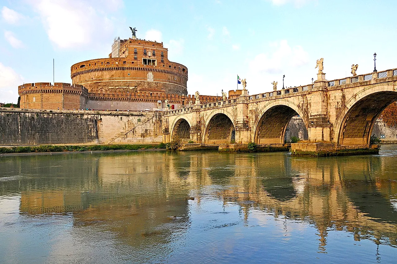 Die Engelsburg und die Engelsbrücke vom Tiberufer aus gesehen, mit den Bögen und der Burg, die sich im ruhigen Wasser unter leicht bewölktem Himmel spiegeln